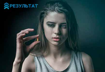 Заплаканная девушка с таблеткой в пальцах